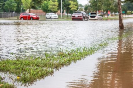 Floodwaters from a storm cause damage to cars and the foundation of homes.