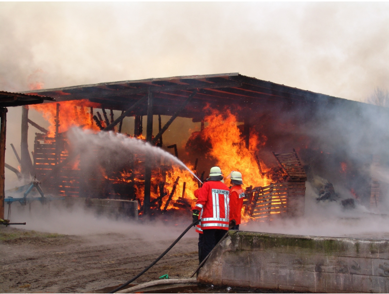 A burning building after a presumed explosion with firefighters