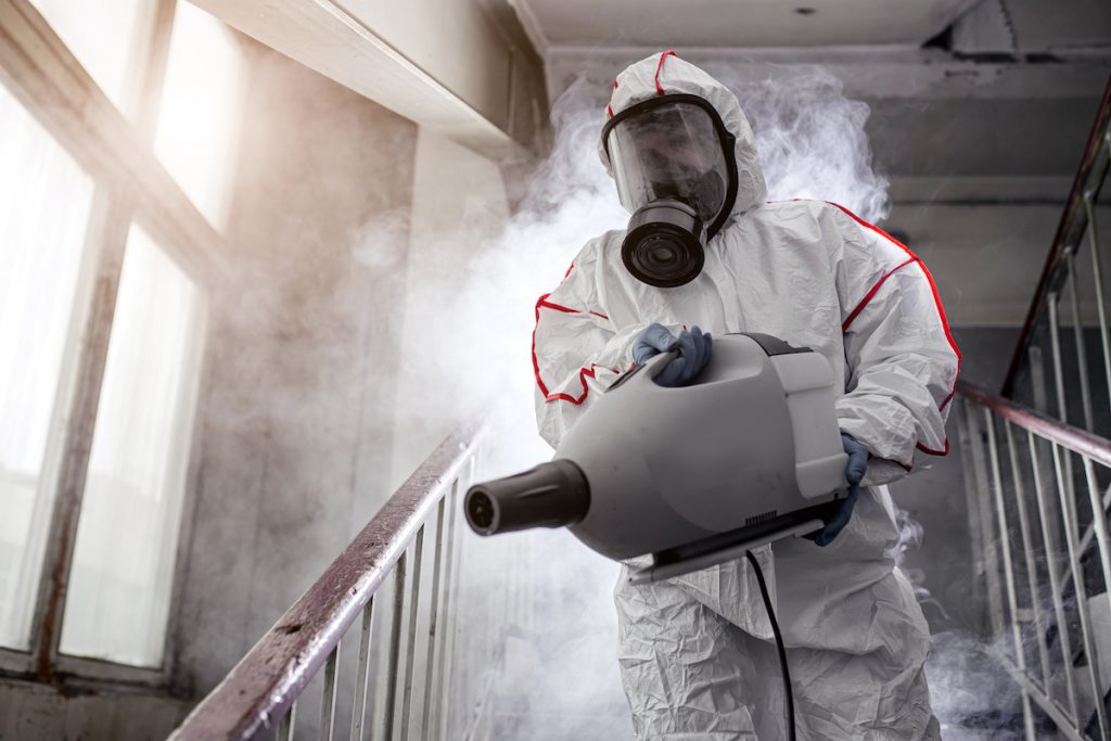 Restoration employee fogging a staircase wearing PPE