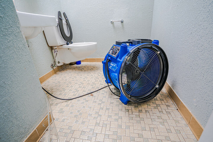 Industrial fans are used to dry a water-damaged bathroom.