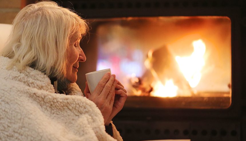 Senior woman relaxing by fireplace