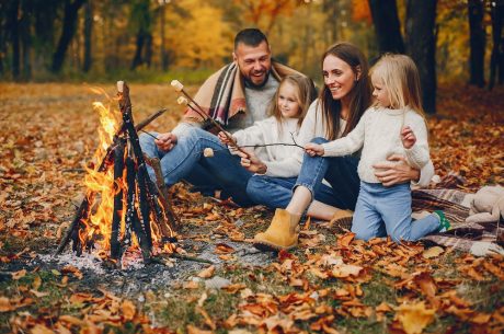 A family sits by a fire roasting marshmallows