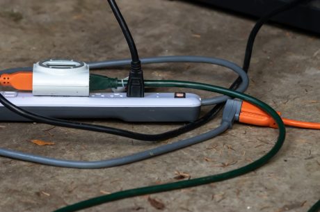 A power strip on carpeted floor with multiple appliances plugged into it