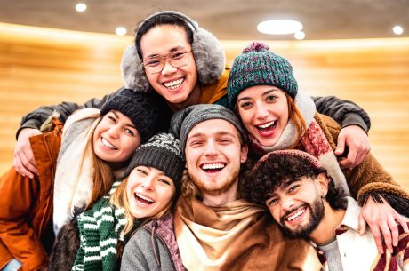 Happy multiracial guys and girls taking selfie in warm fashion clothes