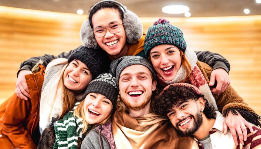 Happy multiracial guys and girls taking selfie in warm fashion clothes