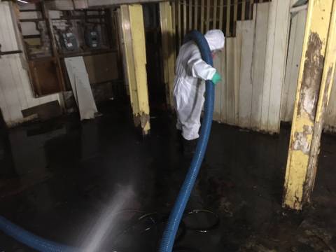 Technician in protective equipment pumping sewage spill