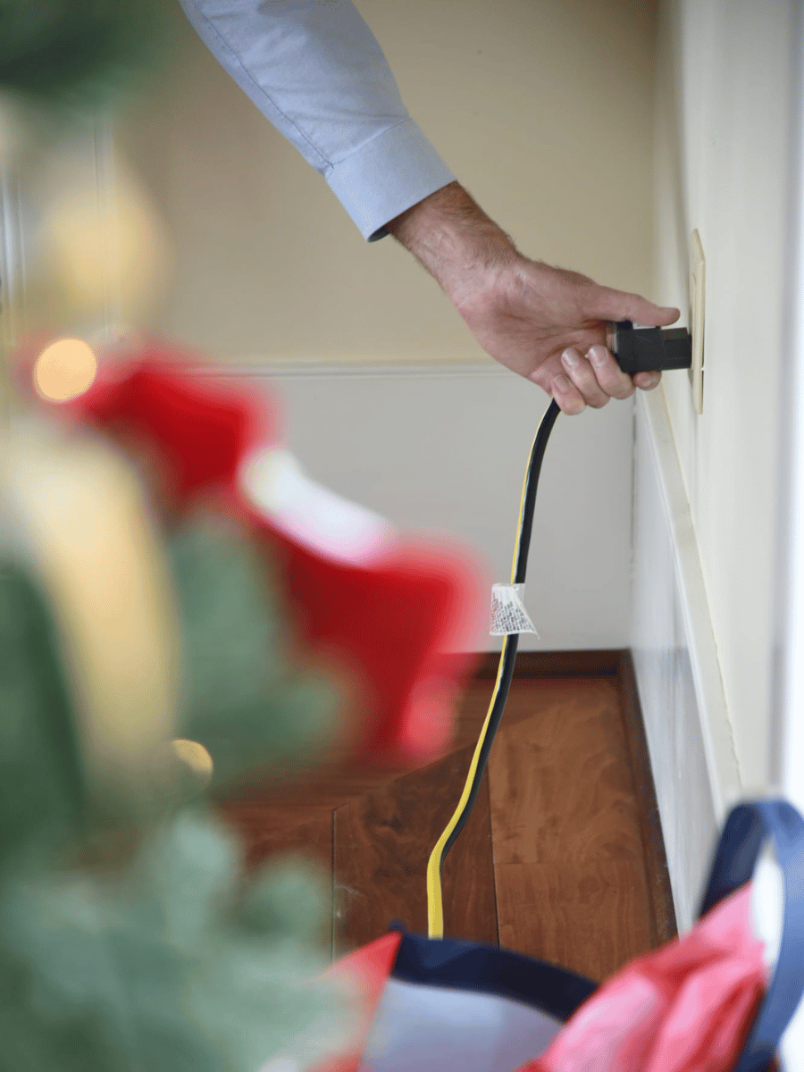 Closeup of hand plugging in Christmas tree lights