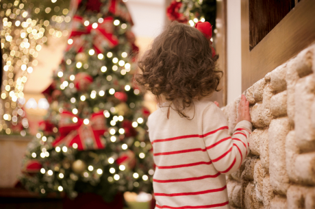 child looking at lighted christmas tree - ready for fire safety for kids tips