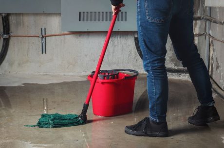 A person mopping up a flooded floor inside a building