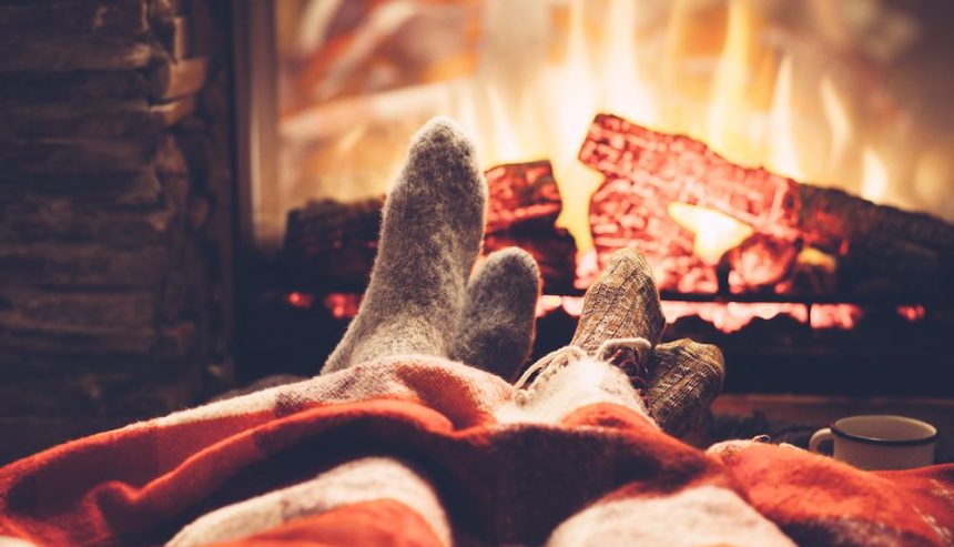 Couple warms their sock-covered feet by the fire