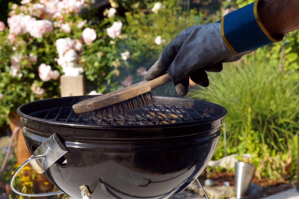 Person cleaning the grill for fire safety 