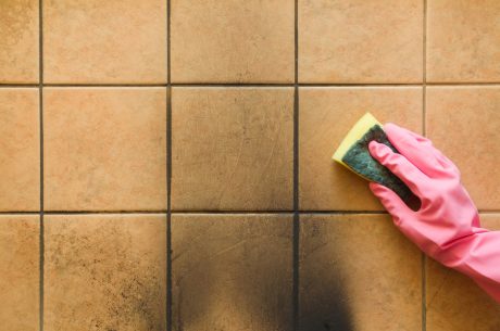 A person cleaning black soot off tile.