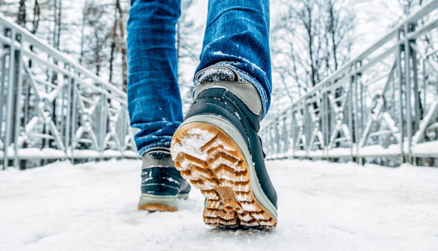 Man's legs in black with black boots walking in the snow. Winter safety tips can help you enjoy the snow.