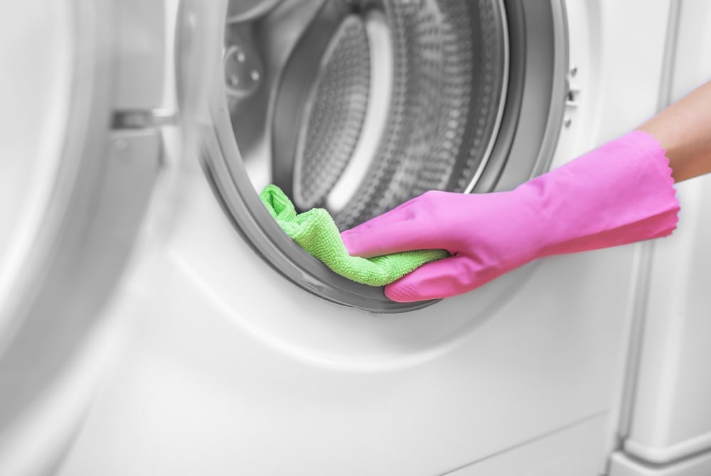 gloved hand cleaning inside of washing machine image for Remove Mold from Washing Machines