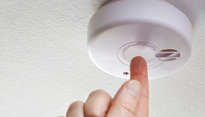 A man conducts smoke alarm maintenance in his Everett home.