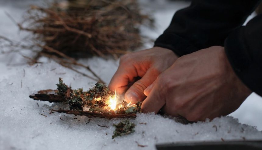 Man lights fire in snow. Winter fire safety tips.