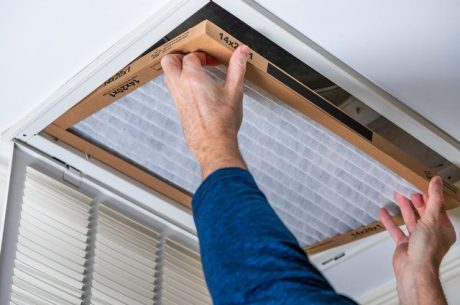 A homeowner changes the air filter to keep the air ducts clean and mold-free.