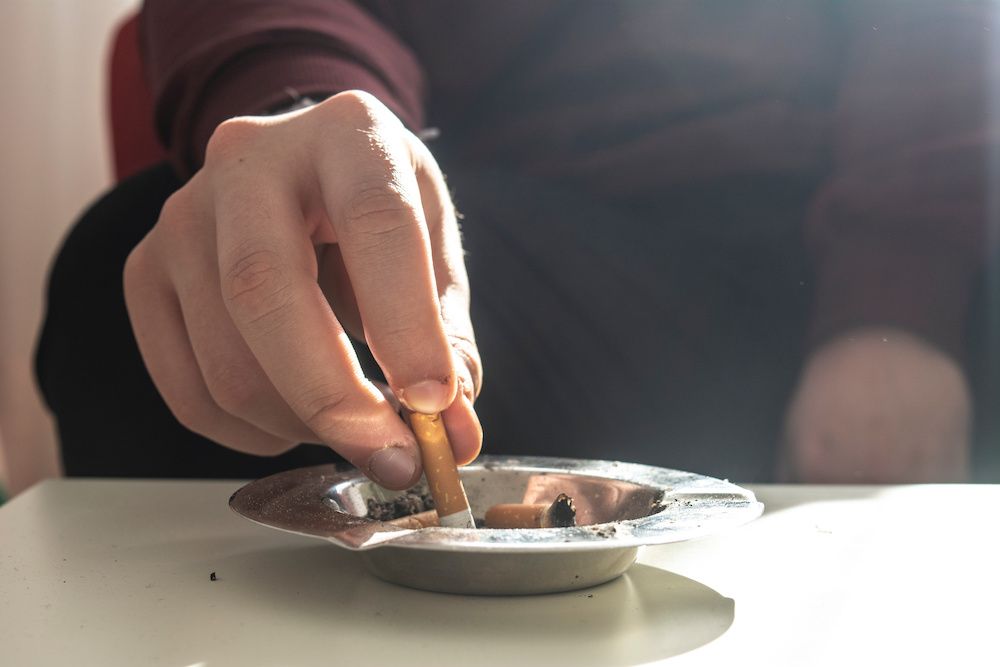 person putting out a cigarette in an ashtray