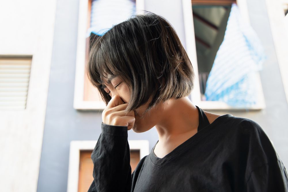 woman with allergies holding her nose