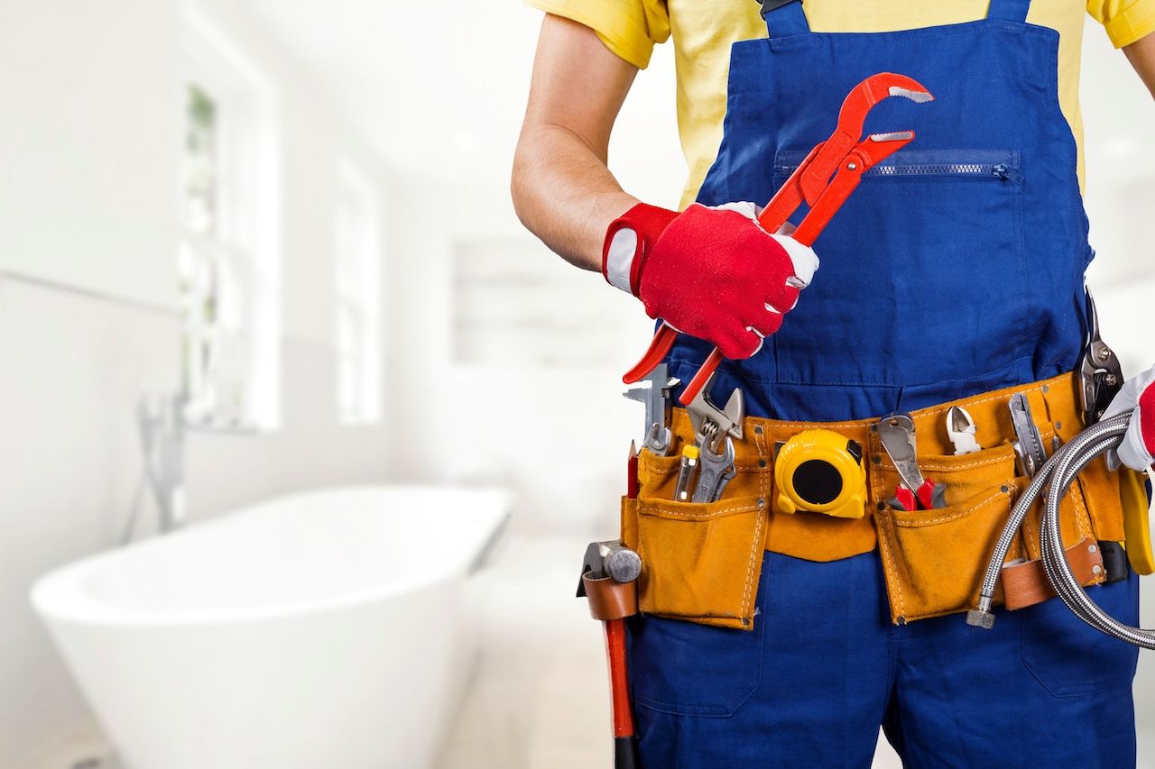 plumber standing in front of a bathtub holding a wrench