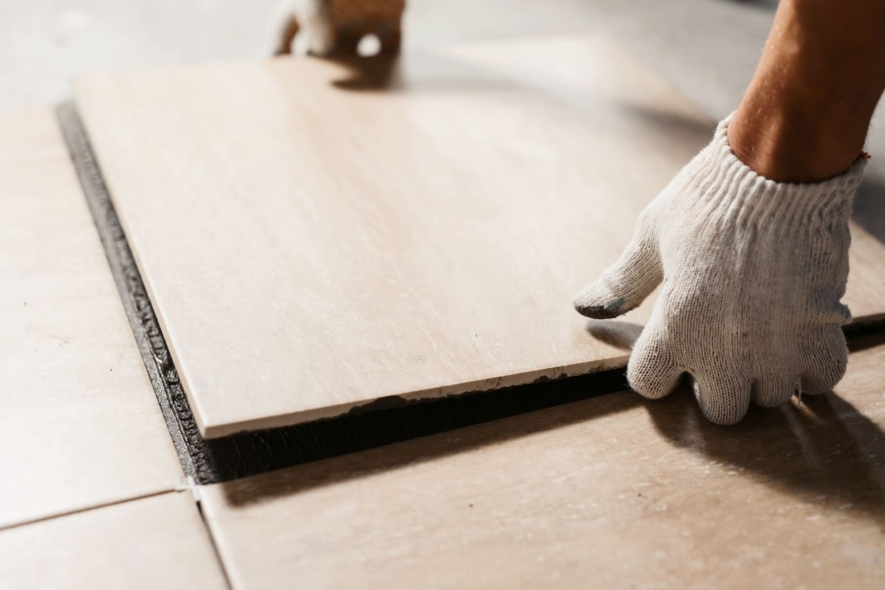 person placing a tile on the floor 