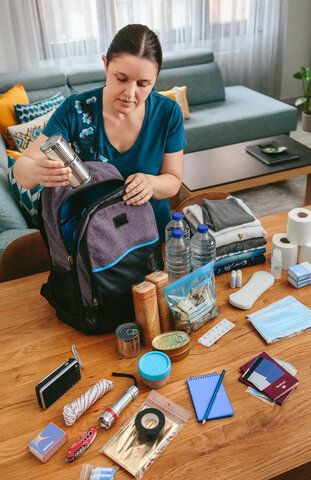 Woman adding essential items in a backpack