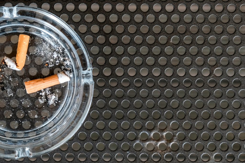 Cigarette butt in an ashtray on black metal background