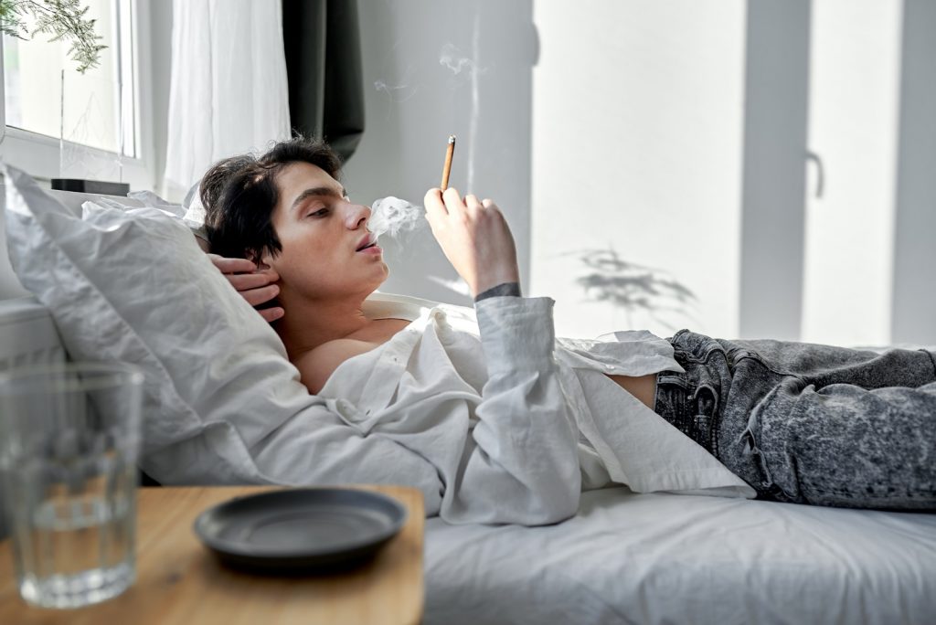 young man smoking in bed